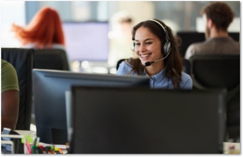 Brown haired woman in a headset working in an open office setting