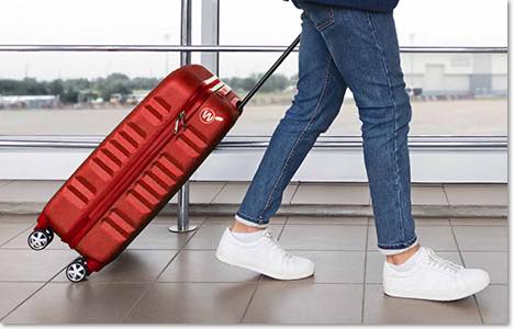 Person walking through the airport with a bright red suitcase